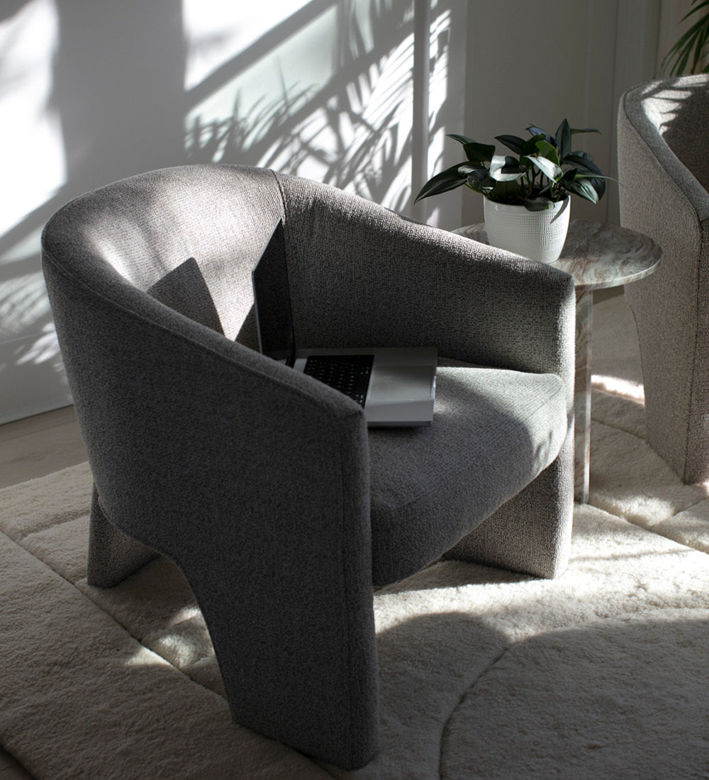 A comfortable chair in a room with beautiful shadows from the leaves outside